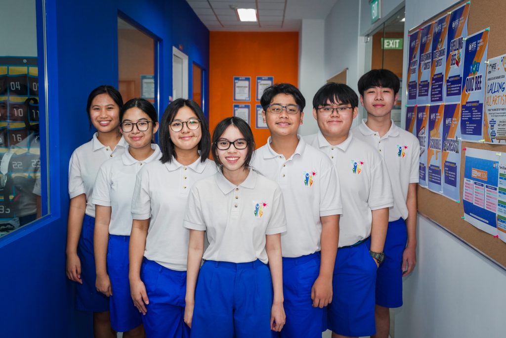Students in uniform standing in a V-shaped formation for a group photo.