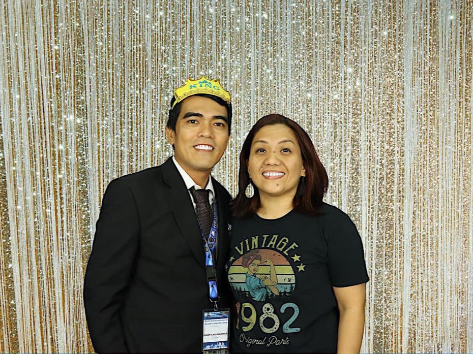 Two school founders posing for a photo in a photo booth, one wearing a crown.
