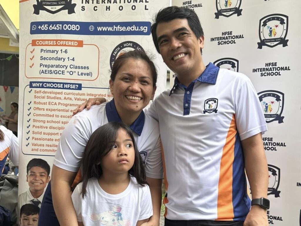 The two school founders wearing their casual uniforms, taking a picture with their daughter.