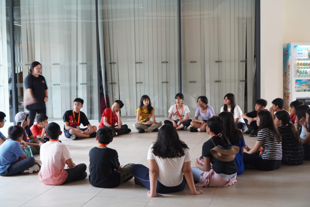 Students seated on the floor in a circle, engaged in a group activity.