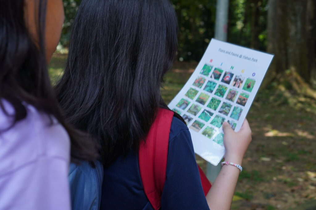 A student holding up a sheet of paper displaying images of various plants.